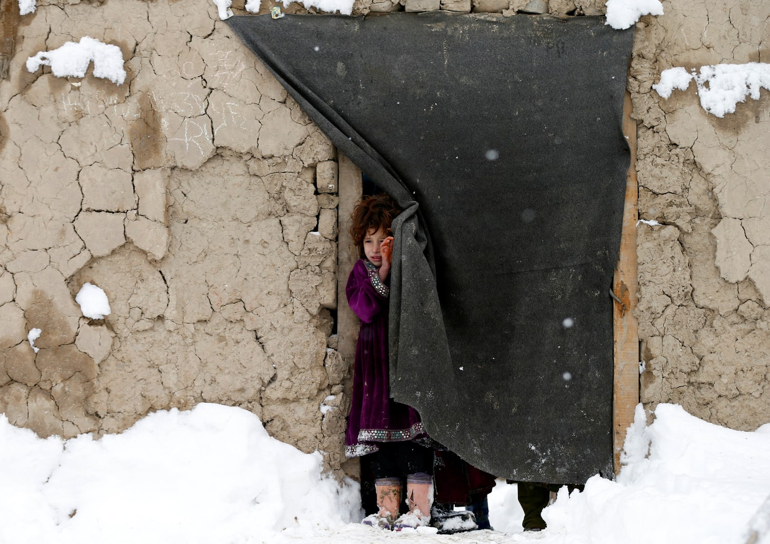 Donate to UNHCR to help refugee children in this winter. A refugee girl standing in snow in Afghanistan, help refugees, donate to UNHCR.