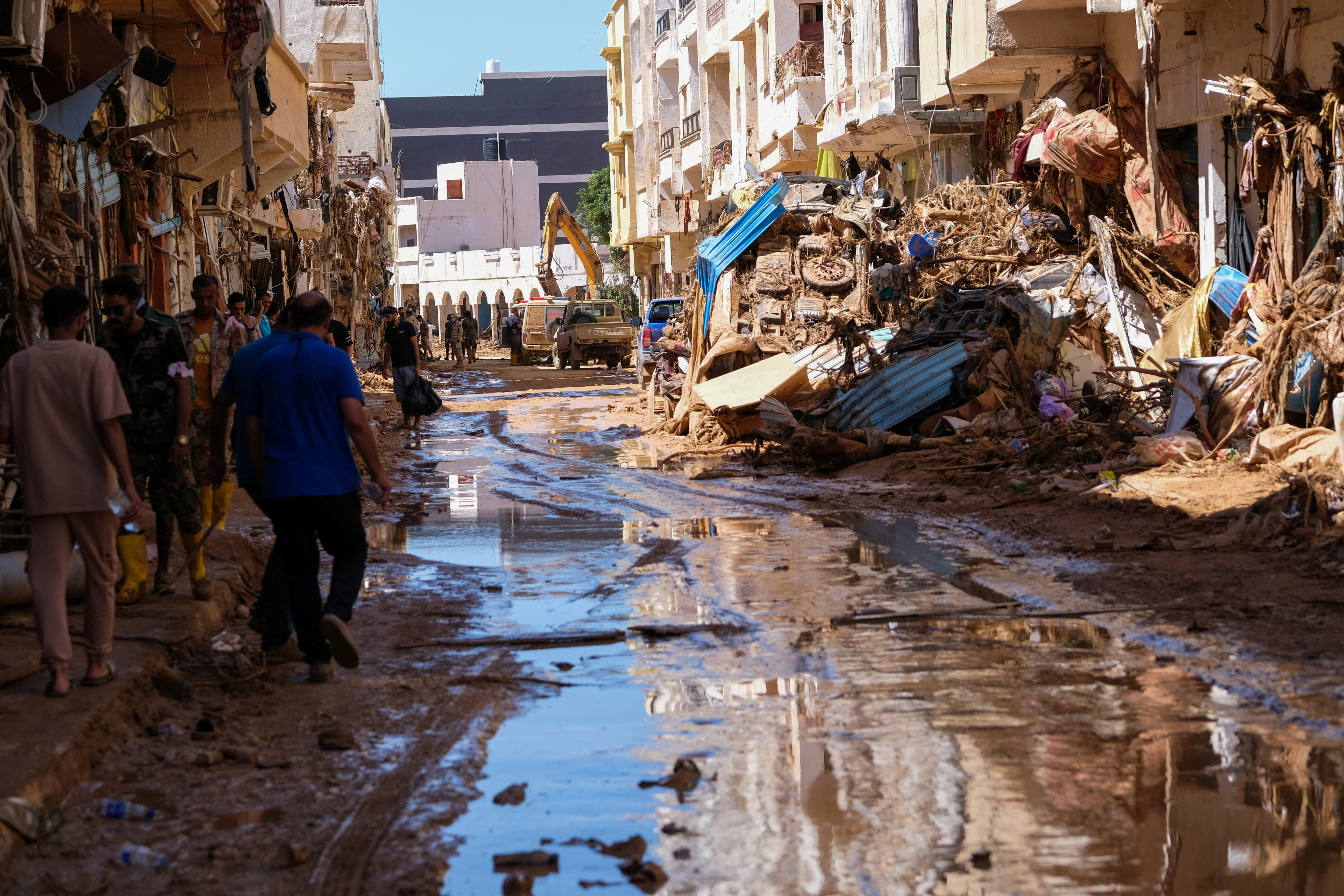People walk in the mud between the rubbles, after a powerful storm and heavy rainfall hit Libya