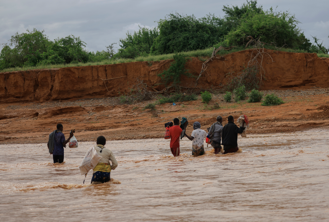 People walk in a flooded Sarole river attempting to cross, near Melkadida in Somali region of Ethiopia.