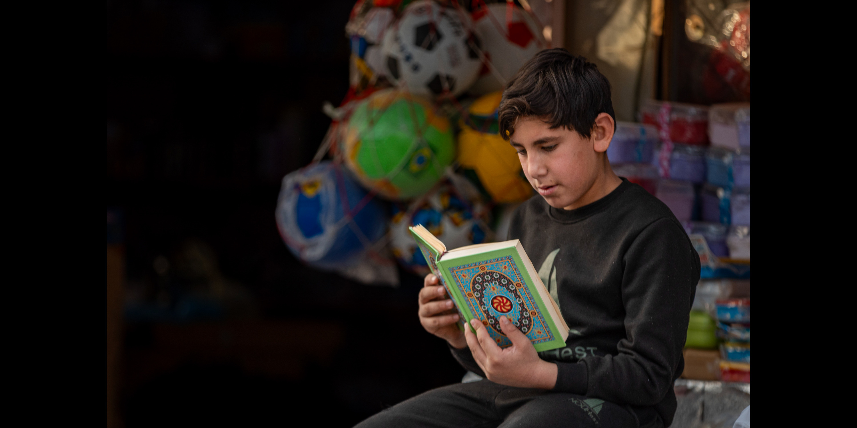 A kid reading the Qur'an at the market