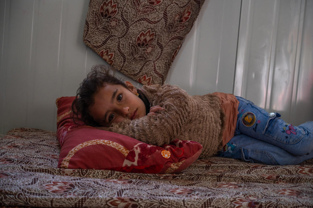 Seven-year-old Retaj AlMaslamani lays on a mattress on the ground inside a shelter in Zaatari refugee camp in Jordan. Her grandmother Ghasiba, 57, cares for her and her two younger sisters since their parents are divorced. When it rains the shelter leaks, and her grandmother struggles to keep them warm and dry.