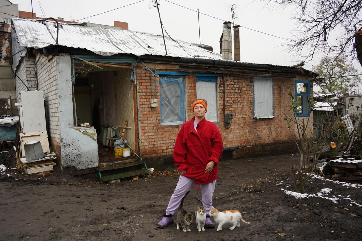 UNHCR: Winter Appeal A displaced woman in front of her house with her dog.