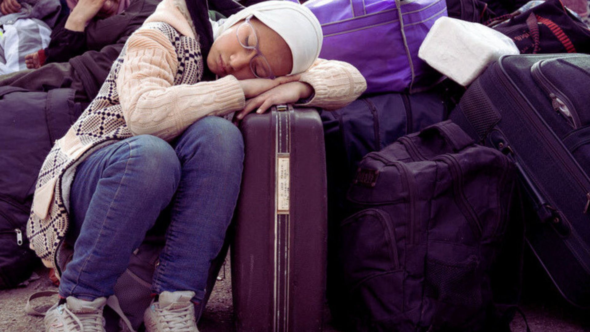 A 12 year old girl sleeps on a suitcase at the Masnaa crossing point, on the Syrian side of the border with Lebanon