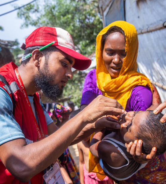 volunteer administers cholera medicine to a young child