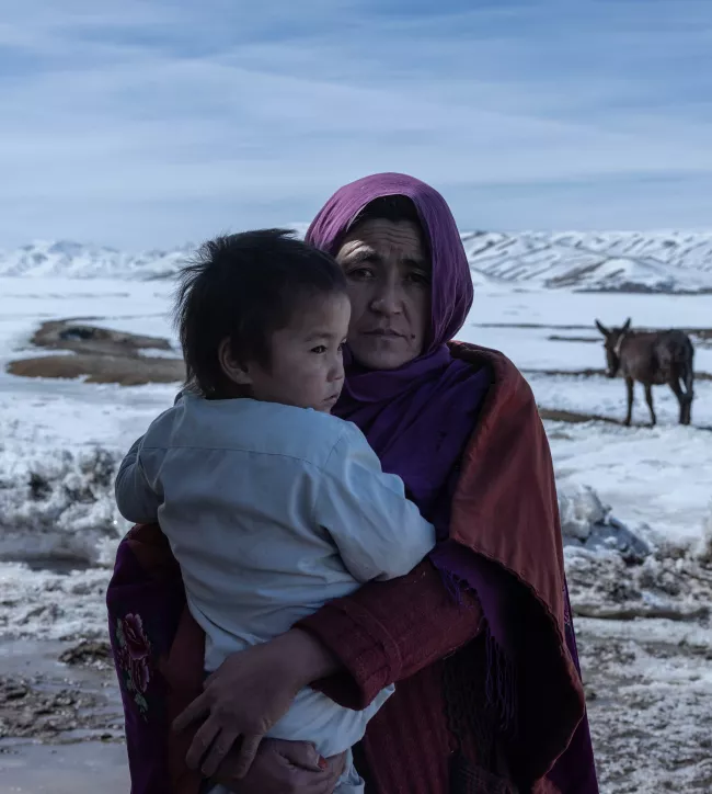 Zahra*, 34, with her young daughter in front of her house in Sabzi, Bamyan province.
