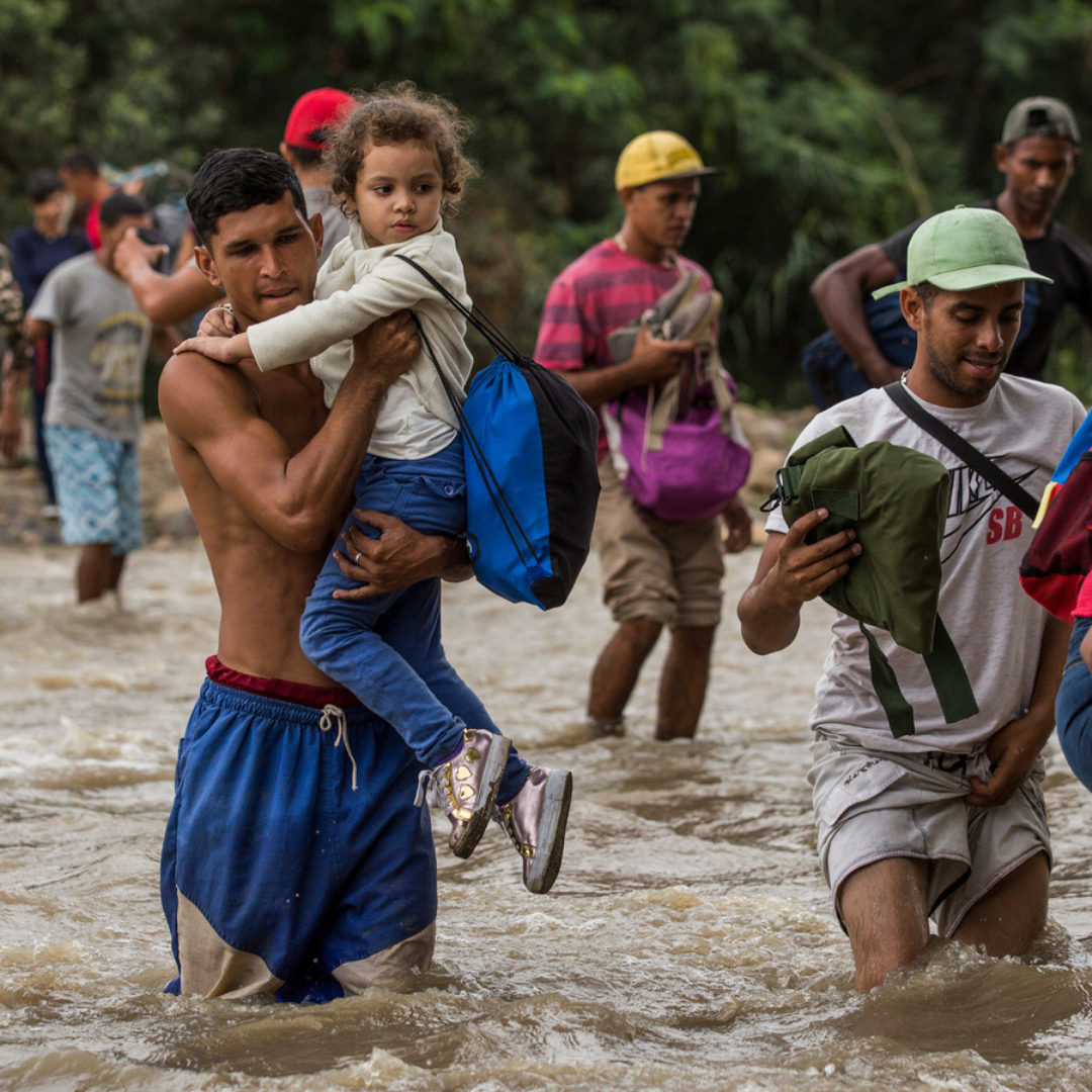 Venezuelan man carrying child across river