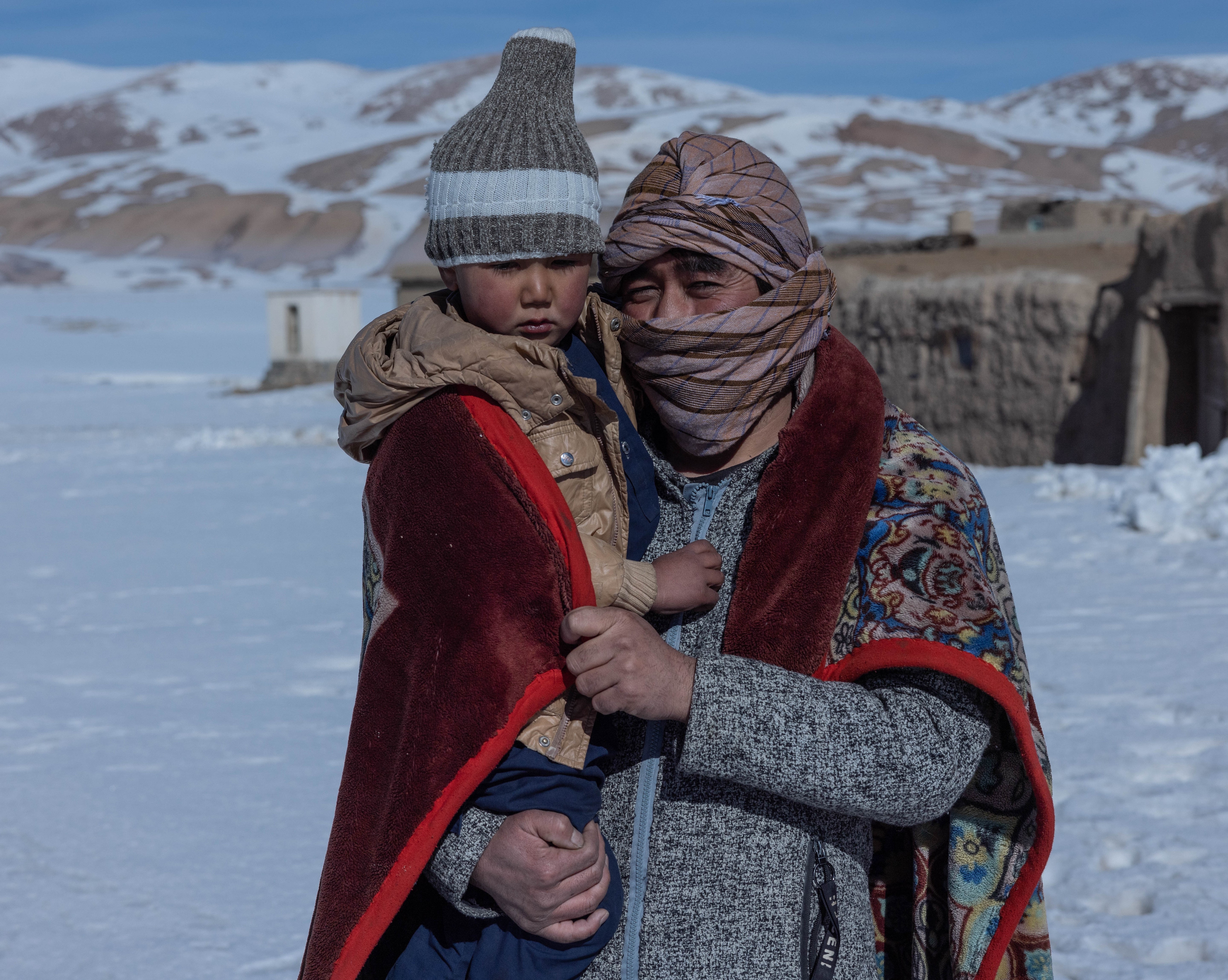 A man and his son outside their small house in Sabzi, Bamyan province