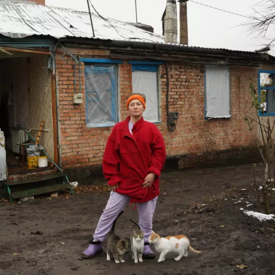 Ukrainian women in front of her bombed house