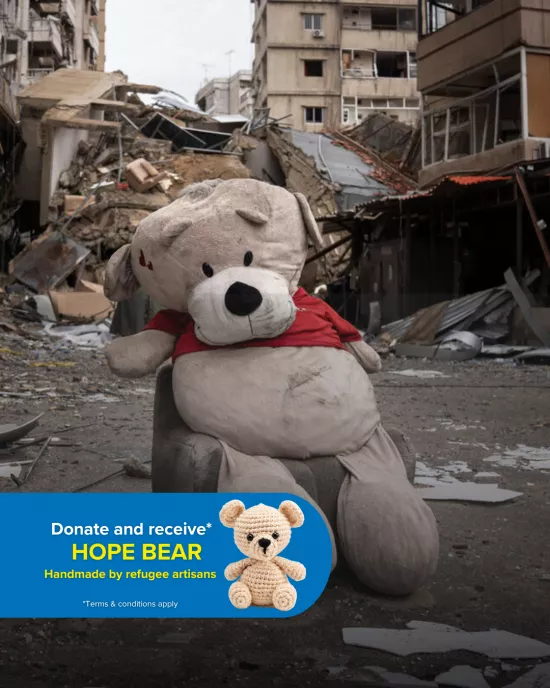 A bear plushie sits in rubble, in a town destroyed by conflict.
