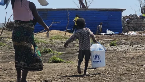 A child and his mum carry UNHCR relief items back to their home in Mozambique